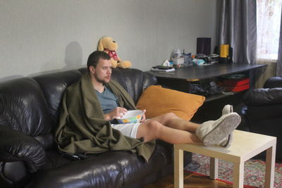 Young man sitting on sofa at home