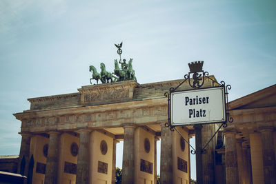 Low angle view of quadriga statue on brandenburg gate against sky in city