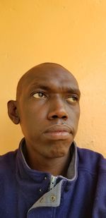 Close-up of thoughtful man against yellow wall