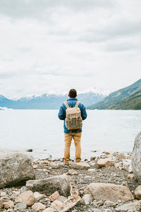 Rear view of man standing on rock against sky