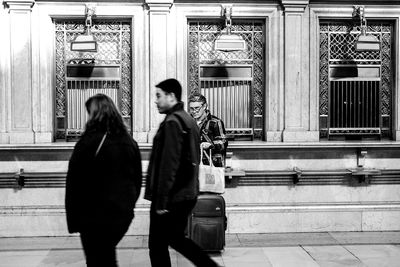 Side view of two people walking in front of building