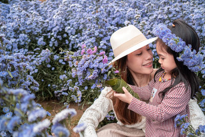 Woman looking at camera while standing by flower plants