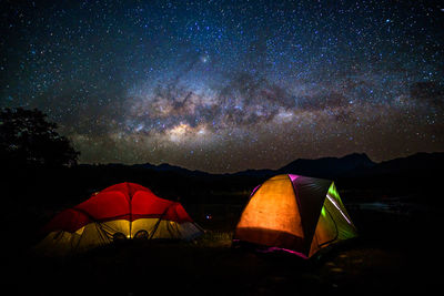 Tent on landscape against star field at night