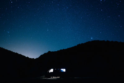 Low angle view of silhouette mountain against star field at night