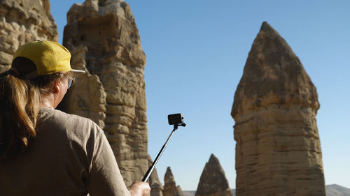 Woman filming herself on action camera against a backdrop of beautiful sandstone cliffs