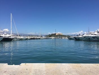 Sailboats moored in harbor against clear blue sky