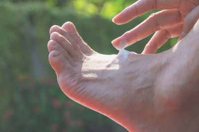 Low section of woman applying cream on leg