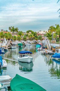 Boats moored in harbor against sky in city