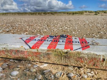 Close-up of text on beach against sky