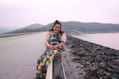 Portrait of smiling woman sitting with pug on railing