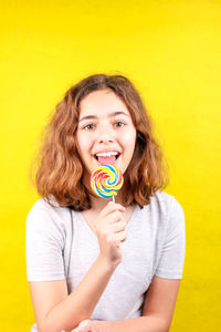 Portrait of a smiling young woman against yellow background