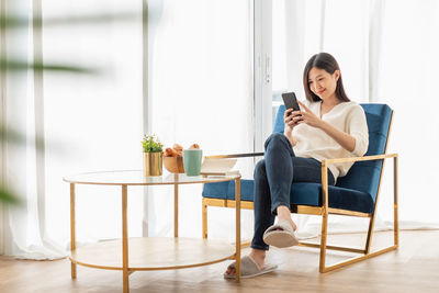 Woman using phone while sitting on chair