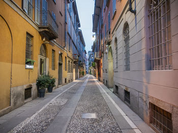 Empty road amidst buildings in city