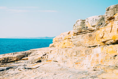 Rock formations by sea against sky