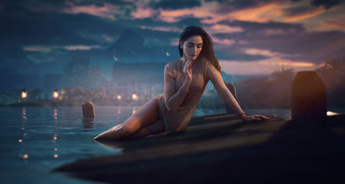 Portrait of young woman in swimming pool against sunset sky