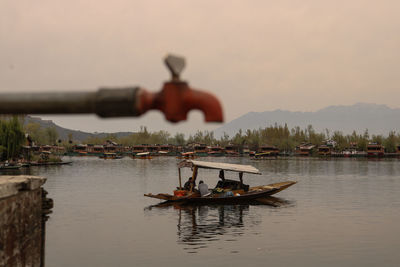 Men in river against sky during sunset