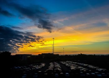 Cars on road against sky during sunset