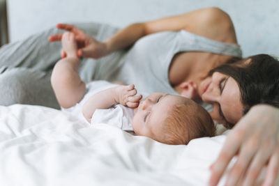 Young mother having fun with cute baby girl on bed, natural tones, love emotion, selective focus