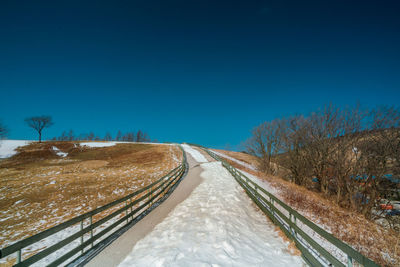 Road against clear blue sky during winter