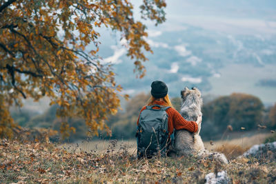 Rear view of man sitting on street during autumn