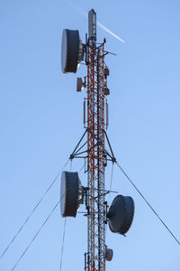 Low angle view of electricity pylon against clear blue sky