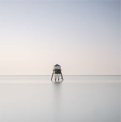 Lifeguard hut amidst sea against clear sky