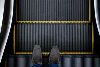 Low section of man standing on escalator