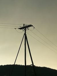 Low angle view of silhouette electricity pylon against sky