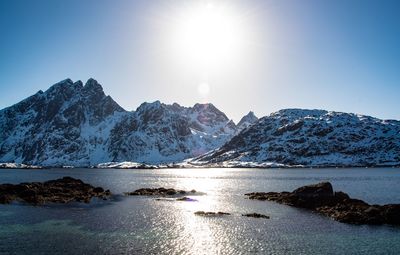 Scenic view of sea and snowcapped mountains on sunny day