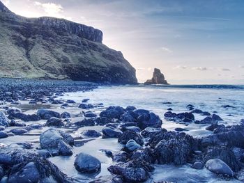 Talisker bay on the isle of skye in scotland. foamy sea, boulders and large cracked rocks in ocean