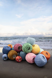 Multi colored umbrellas on table by sea against sky