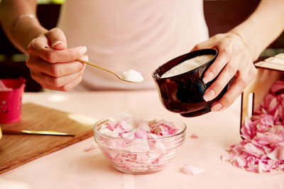 Woman adding sugar to rose petals for natural jam. homemade organic jam preparing tea rose petals. 