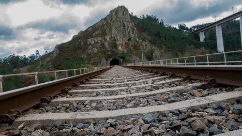 Railroad track by mountain against sky