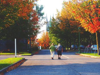 Rear view of people walking in park during autumn