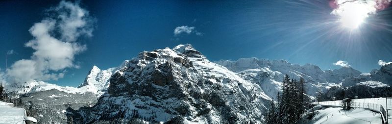 Low angle view of snow covered mountain against blue sky