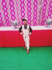 Portrait of boy standing on pink umbrella