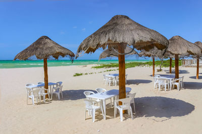 Lounge chairs and parasols on beach against sky