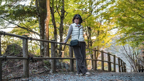 Full length of young woman standing against trees