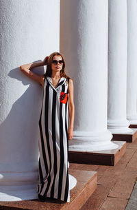 Portrait of young woman standing against wall