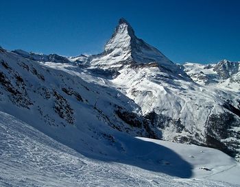 Scenic view of snowcapped mountains against clear blue sky