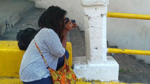 Rear view of woman photographing umbrella