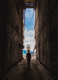 Rear view of man standing amidst buildings