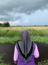 Rear view of woman standing on field against sky