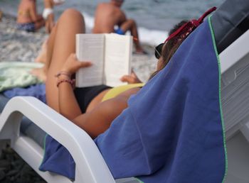 Full length of woman relaxing on lounge chair at beach