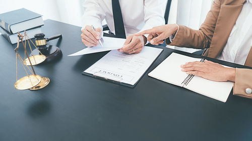 Midsection of man with text on paper at table