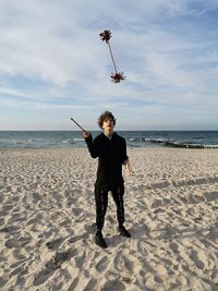 Full length of man on beach against sky, juggling