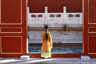 Rear view of woman against door of building