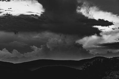 Scenic view of silhouette mountains against cloudy sky