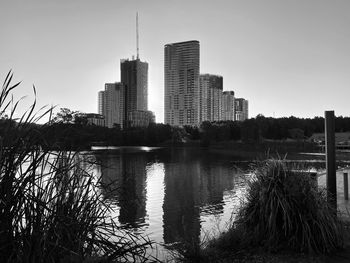 Reflection of buildings in lake against sky in city