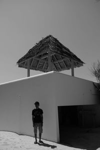 Rear view of woman standing by building against clear sky